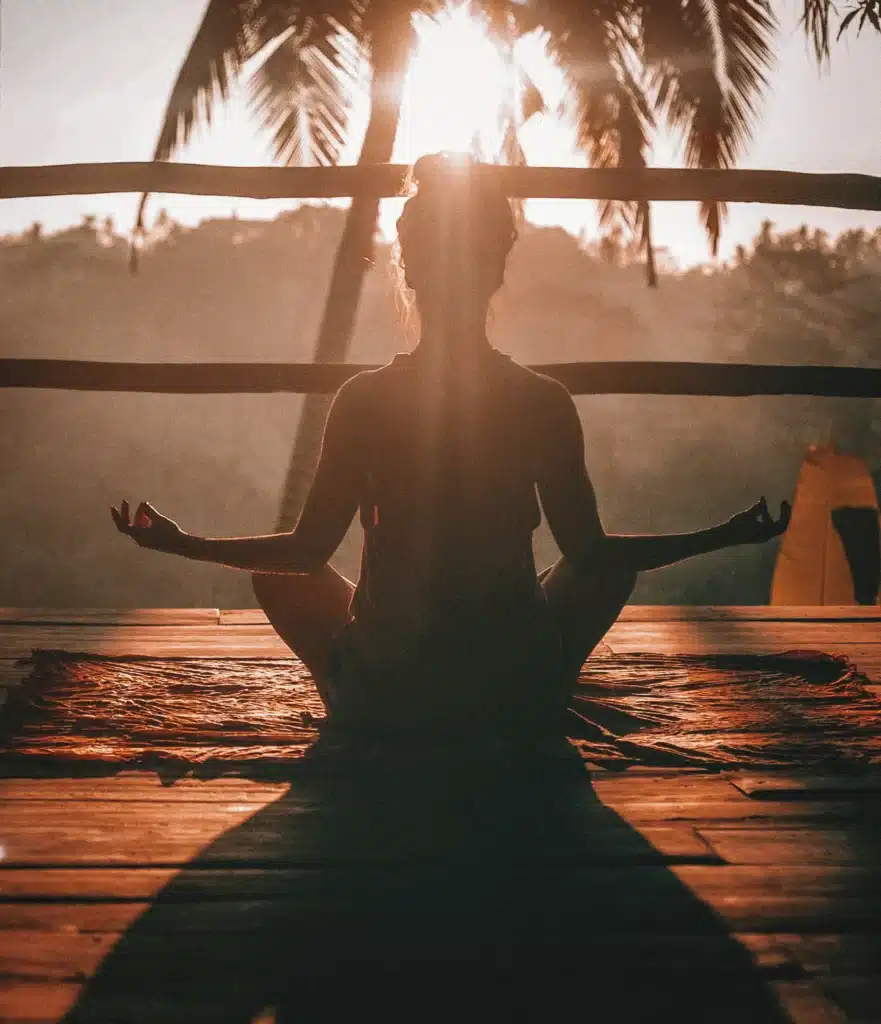 Woman in lotus position facing sunset